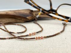 Shiny and bohemian eyeglass necklace chain in copper and gold tones, made with Preciosa Czech crystal seed beads and tiny Sunstone gemstone beads.    Paired with delicate copper plated Japanese Miyuki crystal seed beads and gold touches of the Sunstone gems, this handmade eyeglass chain will definitely create a unique look. Sunstone is linked to luck and good fortune. It instills good nature, heightens intuition and allows the real self to shine through happily. It alleviates stress and increase Adjustable Bronze Beaded Necklaces With Gemstone Beads, Adjustable Bronze Beaded Necklace With Gemstone Beads, Adjustable Bronze Beaded Necklace As Gift, Adjustable Glass Beaded Necklace With Gemstone Beads, Spiritual Glass Beaded Necklaces With Adjustable Fit, Adjustable Bronze Beaded Necklace Gift, Adjustable Glass Gemstone Beaded Necklaces, Brown Glass Beaded Necklaces As Gift, Spiritual Adjustable Glass Beaded Necklaces