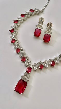 "Gorgeous Brilliantly cut Princess American Diamond Semi Precious (Lab Created) Ruby Colored Stone in prong setting all over. This necklace is full of lusture and looks very elegant. Style this perfect versatile cocktail necklace set with any Indian / Indo Western Attire.   WHAT GOES IN  👉🏻American Diamond / Cubic Zirconia AD Necklace Set with earrings in silver finish.  👉🏻Necklace Length : 20-24\" inches approximately. 👉🏻Earrings Size : 1.5\" inches. (light weight) ❤️We want you to LOVE y Formal Crystal Bridal Necklace With Prong Setting, Classic Diamond Cut Bridal Necklace For Party, Red Prong Set Necklace For Wedding, Classic Bridal Necklace With Diamond Cut For Party, Red Necklace With Prong Setting For Wedding, Red Wedding Necklace With Prong Setting, Classic Party Bridal Necklace With Diamond Cut, Cocktail Necklace, Wedding Necklace Set