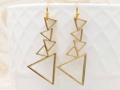 "These are chic and unique golden cascading triangle earrings. They hang underneath golden plated French ear wires. The earrings measure about 49mm (1.9 inches) long from the top of the ear wire to the bottom of the triangle. A wonderful idea for gift giving or as a little treat for yourself. Your item will arrive in gift wrap and ready to gift. Measurements and details: Length: 49mm (1.9\") Triangle: 41mm x 20mm Earwire: golden plated PLEASE NOTE: All Sales Are Final. No refunds, returns or exc Triangle Earrings Dangle, Boho Chic Minimalist, Rough Stone Jewelry, Gold Feather Earrings, Earrings Boho Chic, Earrings Triangle, Abstract Mountain, Bohemian Minimalist, Dangle Earrings Gold