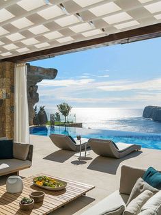 an outdoor living area with couches, chairs and a table by the swimming pool