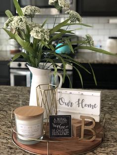 a vase with flowers and some candles on a tray in front of a sign that says our home