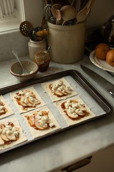 small pizzas are lined up on a baking sheet and ready to go into the oven