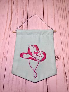 a pink and white cowboy hat hanging on a wooden wall