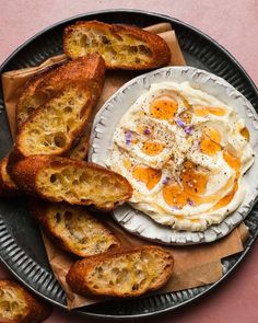 an egg and bread dish on a plate with some slices of toast next to it