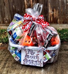 a plastic basket filled with lots of different types of sports items in front of a wooden fence