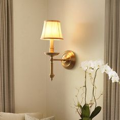 a living room with a couch, lamp and flowers on the table in front of it