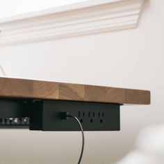 an electronic device is plugged in to a wall mounted power strip on a shelf