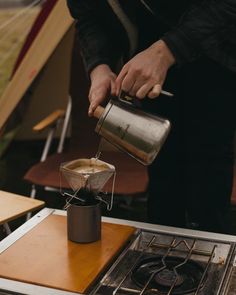 a person pours water into a pot on top of an open burner stove