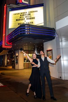 a man and woman posing in front of a marquee for the musical theater