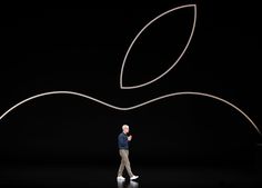 an apple logo is shown in front of a man walking through the dark with his hand on his hip