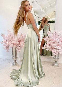 a woman standing in front of a mirror wearing a long green dress with open back