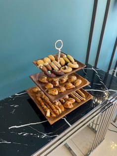 three tiered trays filled with pastries on top of a marble countertop