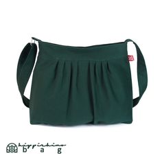 a green purse with pleating on the front and shoulder strap, sitting against a white background