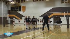 a group of women standing on top of a gym floor next to each other holding volleyball racquets