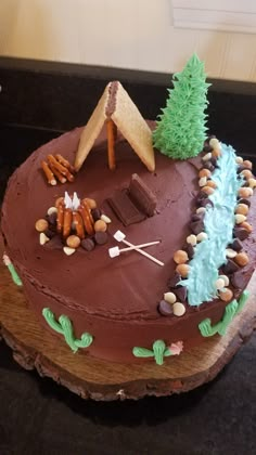 a cake that is shaped like a camper and tent on top of a tree stump