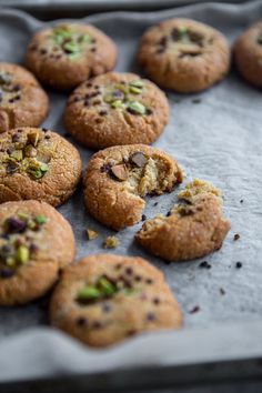 several cookies with nuts and pistachios are on a baking sheet, ready to be eaten