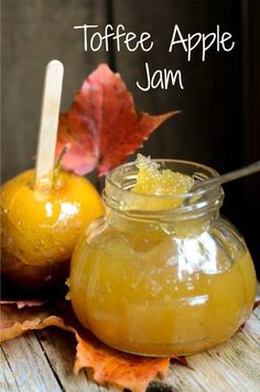 an apple jam in a glass jar next to two oranges