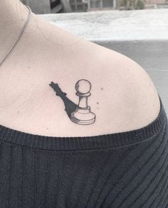 a woman's shoulder with a black and white chess piece tattoo