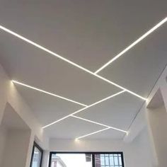 an empty room with white walls and ceiling lights on the ceiling is lit by recessed lighting