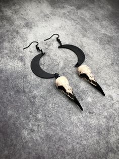 a pair of black and white earrings with skulls hanging from it's sides on a gray surface