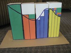 an origami box with colorful bars on it sitting on top of a piece of cardboard