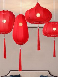 three red lanterns hanging from the ceiling above a bed with blue pillows and throw pillows