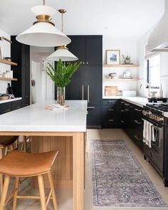 a kitchen with black cabinets, white counter tops and an area rug on the floor