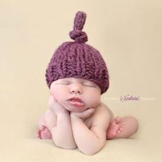 a newborn baby wearing a purple knitted hat