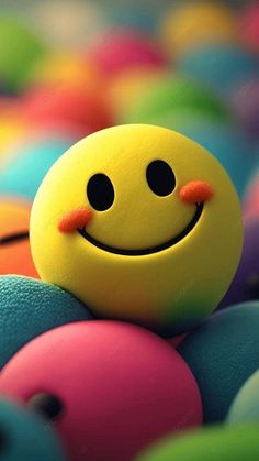 a yellow smiley face sitting on top of colorful balls