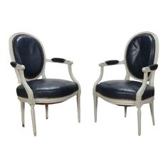 a pair of chairs with black leather upholstered on the back and armrests