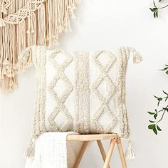 a white pillow sitting on top of a wooden chair next to a potted plant