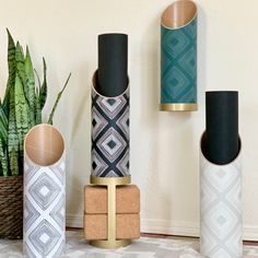 three decorative vases sitting on top of each other next to a potted plant