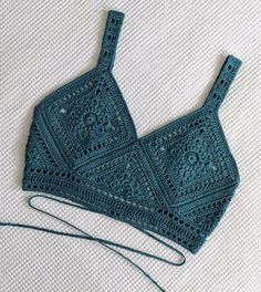 a crocheted bra hanging from a hook on top of a white table cloth