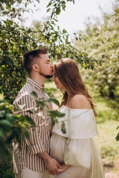 a man and woman kissing in an apple orchard