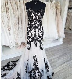 a black and white dress on display in front of dresses hanging from racks at a bridal gown shop