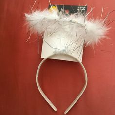 a white headband with feathers on it sitting on top of a red wall next to a book