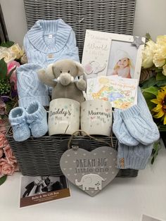 a basket filled with baby's items on top of a table next to flowers