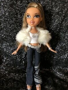 a barbie doll wearing jeans and a white top with fur collar on her head,