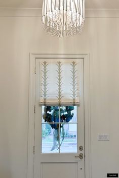 a chandelier hanging from the ceiling in front of a door with a window