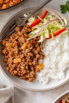 a plate with rice, meat and vegetables next to a bowl full of other food