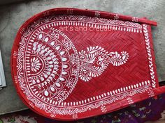 a red tray with white designs on it sitting next to a person's hand