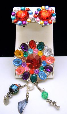 "Vintage Colorful Rhinestone Clip On Earrings Rhinestone Brooch with Cross, Glass Trade Bead, Faux Pearl, Heart, and Flower Accents.  Appears to be Hand Made, but is Nicely Done. Marks - None. Each Earring Measures 1\" Diameter. and 1\" Wide, Brooch Measures 4 1/4\" Long and 2 1/8\" Wide. Condition is Excellent with No Flaws and Minimal Wear or Aging." Multicolor Costume Jewelry Brooches For Weddings, Multicolor Party Jewelry With Brooch, Multicolor Jeweled Clip-on Earrings As A Gift, Luxury Multicolor Clip-on Earrings, Collectible Retro Clip-on Jewelry, Vintage Multicolor Clip-on Jewelry, Vintage Multicolor Drop Clip-on Earrings, Vintage Silver Clip-on Earrings With Rhinestones, Trade Beads