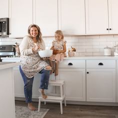 a woman and her daughter sitting on a stool in the kitchen preparing food for dinner