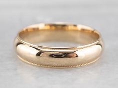 a gold wedding ring on a white surface