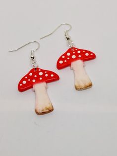 These brightly coloured toadstools look lovely as earrings and will brighten any outfit.  They are hand made from polymer clay, hand painted with pastels and have enamel dots to decorate.  They are glossed for a protective coat.  The ear wires are silver plated. Cute Handmade Mushroom Earrings, Cute Handmade Mushroom-shaped Earrings, Handmade Cute Mushroom Earrings, Whimsical Mushroom-shaped Earrings For Gifts, Cute Red Hand-painted Jewelry, Cute Mushroom-shaped Earrings For Gifts, Cute Red Hand Painted Jewelry, Cute Hand Painted Red Jewelry, Whimsical Red Hand Painted Jewelry