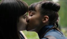 two young women kissing each other in the park