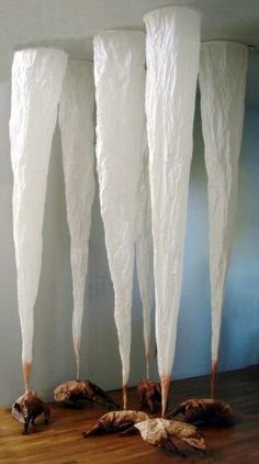 three tall white vases sitting on top of a wooden floor