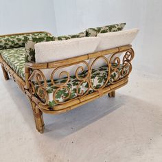 a couch made out of bamboo with green and white fabric on the backrests