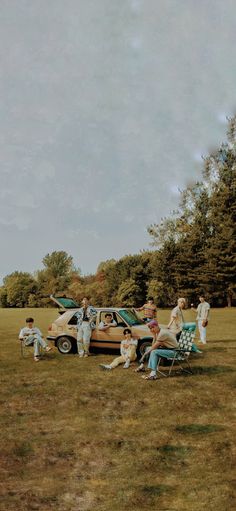 several people sitting in lawn chairs next to an old car and another person standing near by