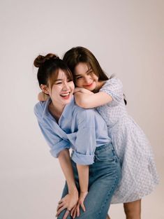 two young women hugging each other while posing for the camera in front of a white background